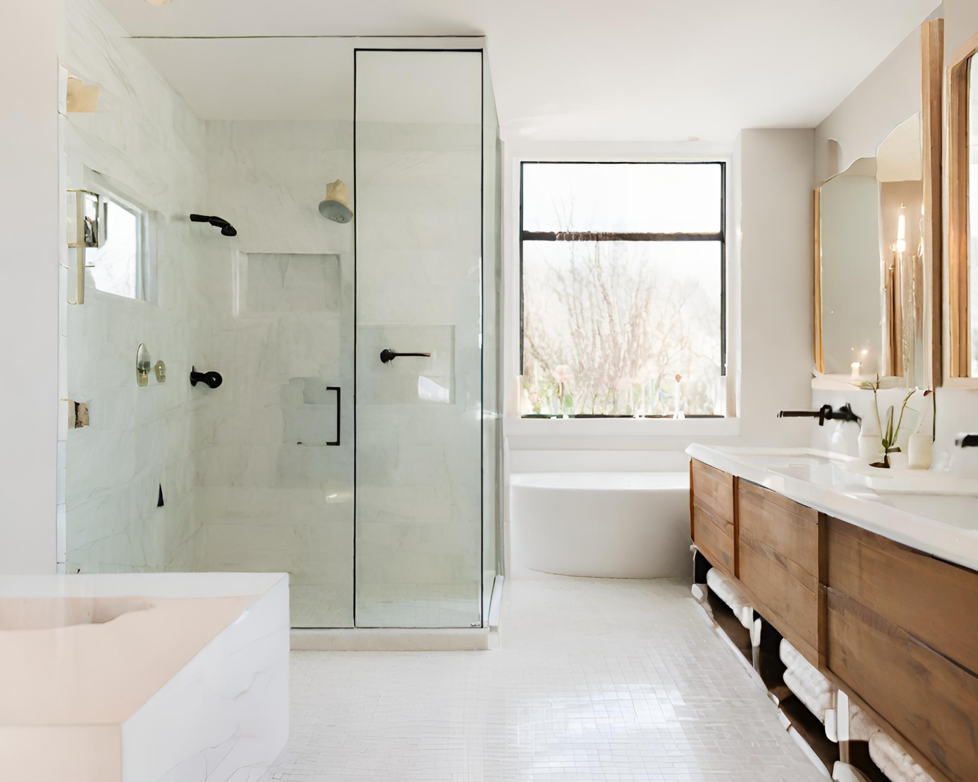 spacious bathroom with white flooring, white bathtub by the window. Wooden bathroom cabinets and white tone countertop and sink. Spacious standing shower with tall and clear shower doors all around and white stone on all walls in the shower.