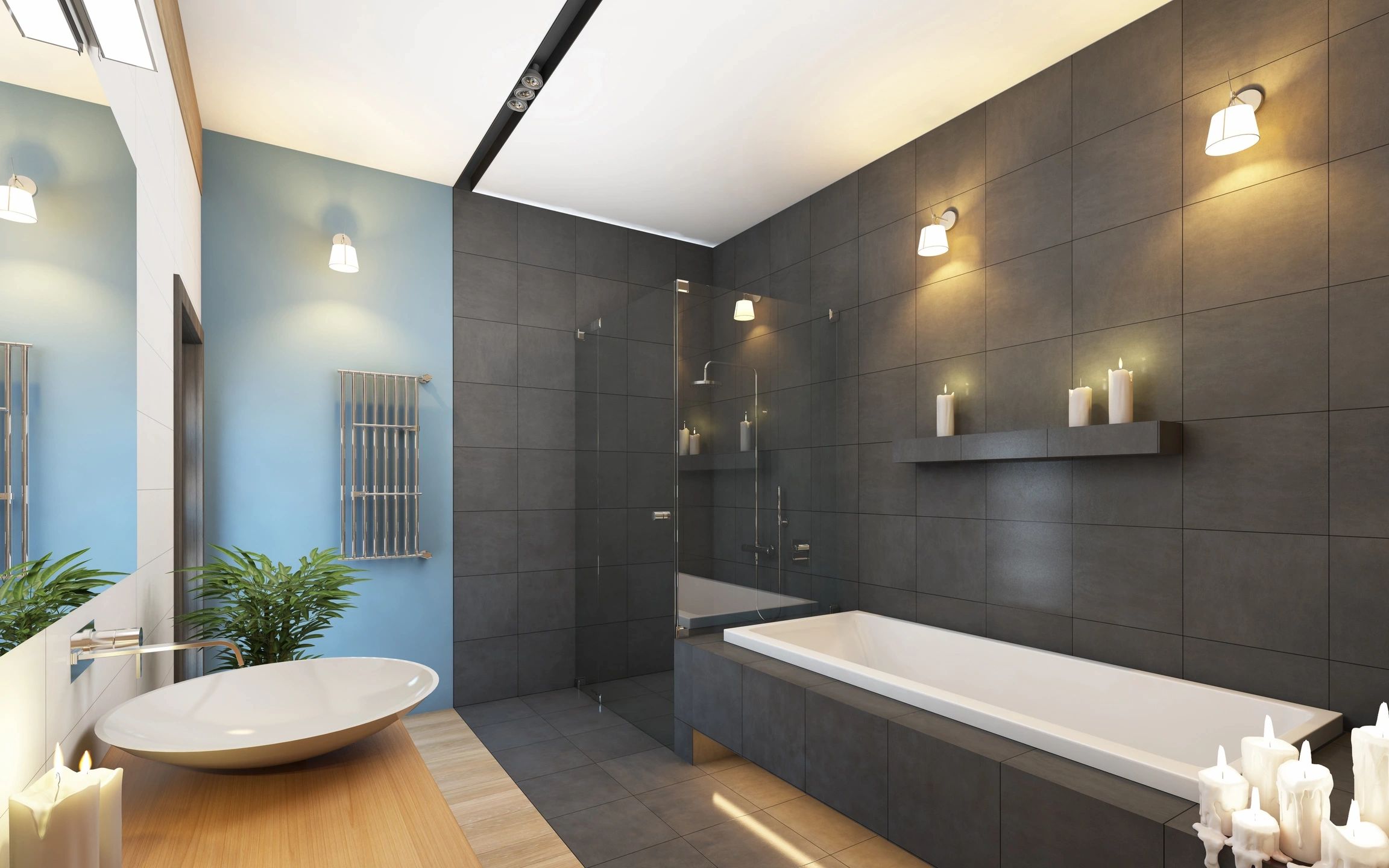 Light black stone flooring and wall on half the bathroom where the shower is with a light black bathtub that is white inside. small shower counter in the middle of the shower and blue walls on the other side of the bathroom with light wood countertop and white stone sink infront of the shower.